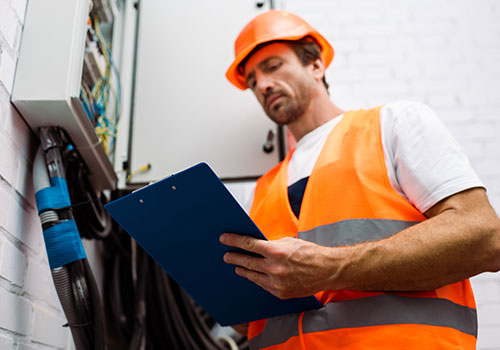 Electrical contractor wearing hi-visibility vest conducting electrical audit